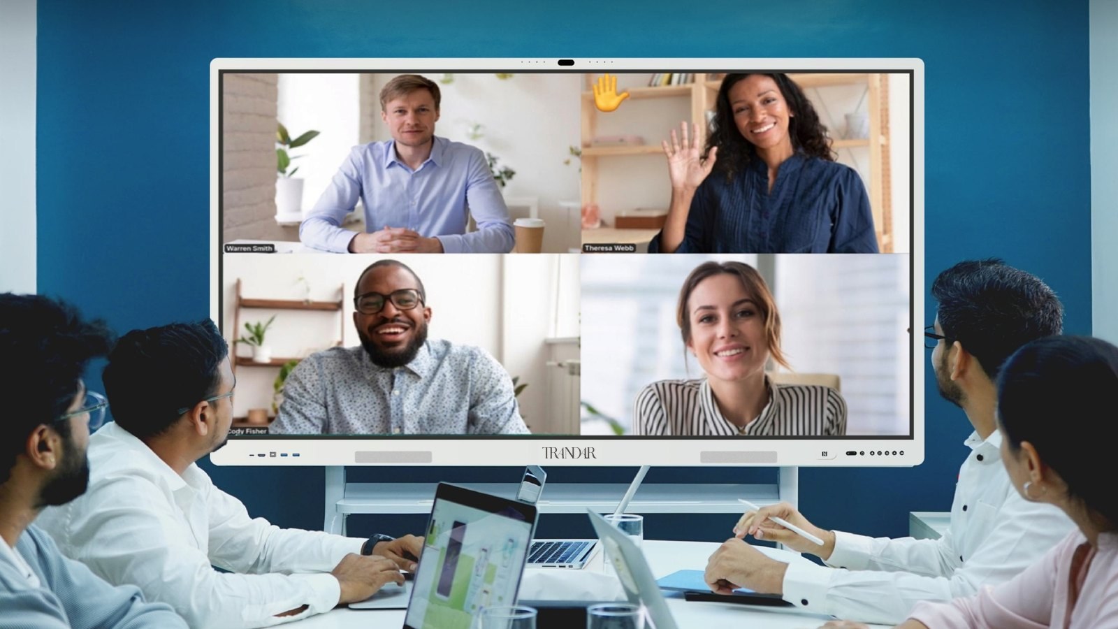 A team around a table on a video call with four remote colleagues on the whiteboard