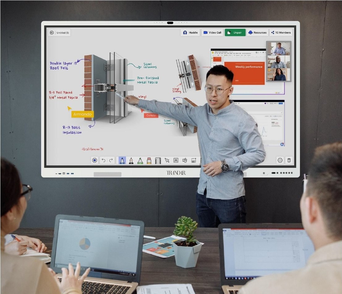 An architect presents a wall-mounted whiteboard in a huddle room, with a remote participant on screen